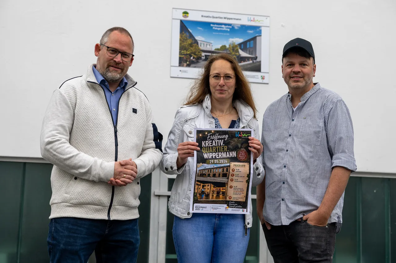 Bürgermeister Armin Kibbert, Yvonne Behnke und Matthias Clever halten ein Plakat für die Eröffnung des Kreativ.Quartier.Wippermann am 29. Mai im Denkhof Halver hoch.