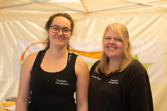 Zwei lächelnde Frauen in schwarzen Oberteilen mit dem Schriftzug „Tierheim Dornbusch“.