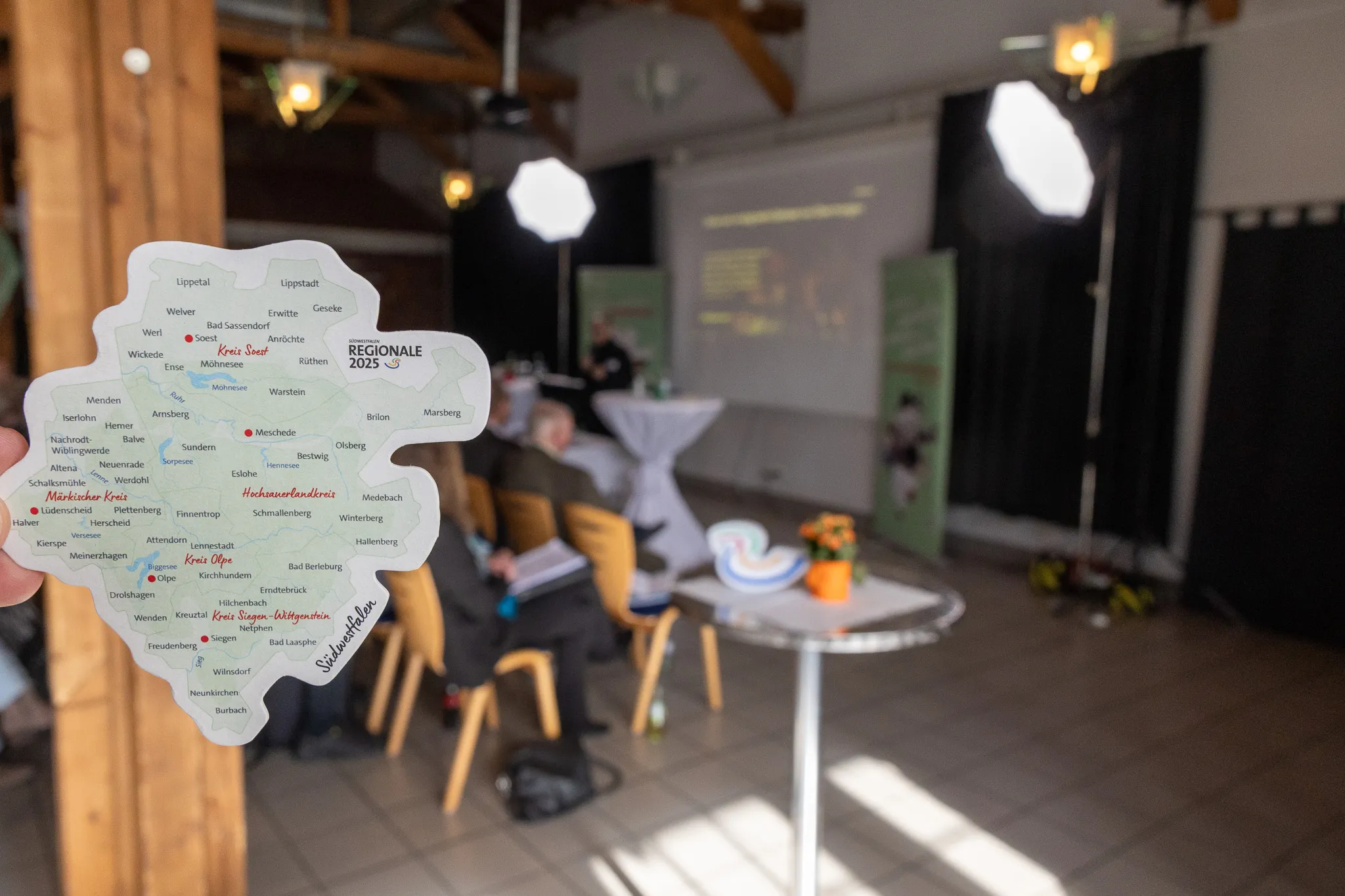 Karte von Südwestfalen mit eingezeichneten Städten und Kreisen, hervorgehoben der Kreis Olpe. Im Vordergrund ein Namensschild mit der Aufschrift „Steigenberger“.