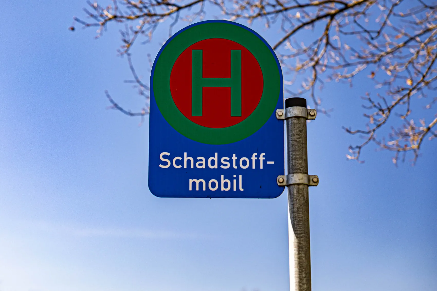 Blaues Verkehrsschild mit rotem „H“ in einem grünen Kreis, darunter der Text „Schadstoffmobil“. Das Schild kennzeichnet eine Haltestelle für die mobile Schadstoffsammlung.