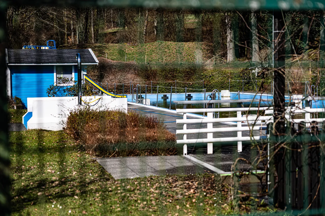 Das leere Freibad Valbert in Meinerzhagen mit blauem Umkleidetrakt, Rutsche und Becken im Winter.