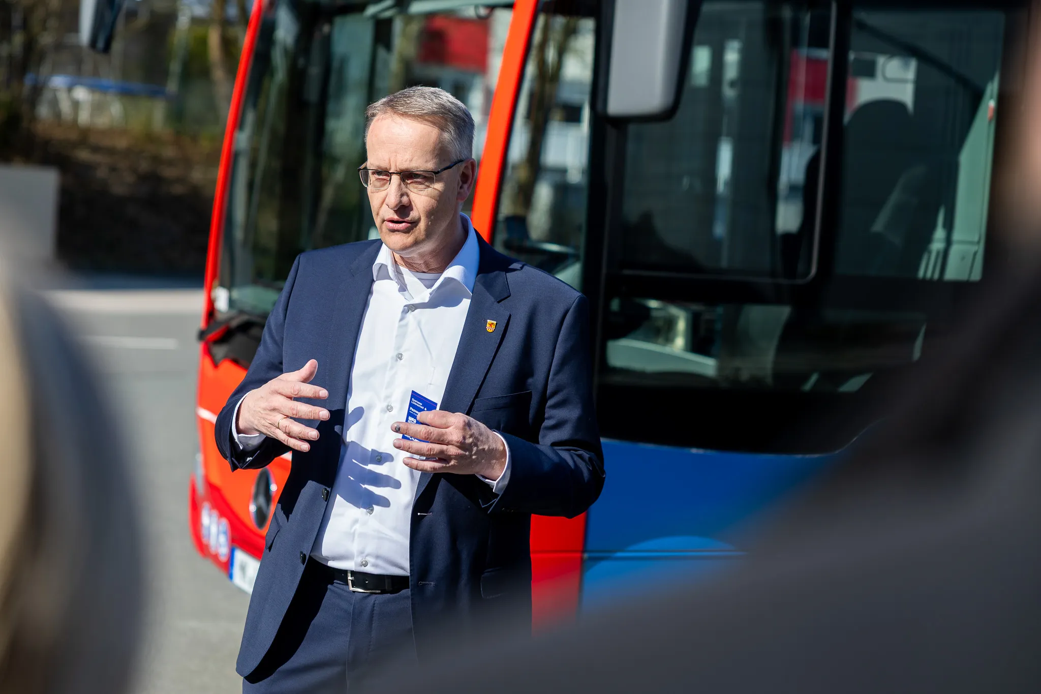 Bürgermeister Uwe Schmalenbach vor einem roten Bus, gestikulierend während eines Pressetermins zum Nachtbus N7 der MVG.