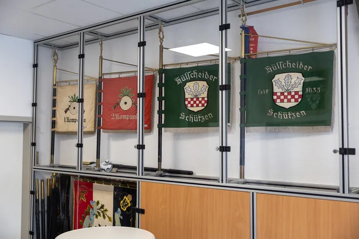 Mehrere historische Banner der Hülscheider Schützen hängen an einer Wand, darunter ein Banner mit der Jahreszahl 1635 und einem Wappen.