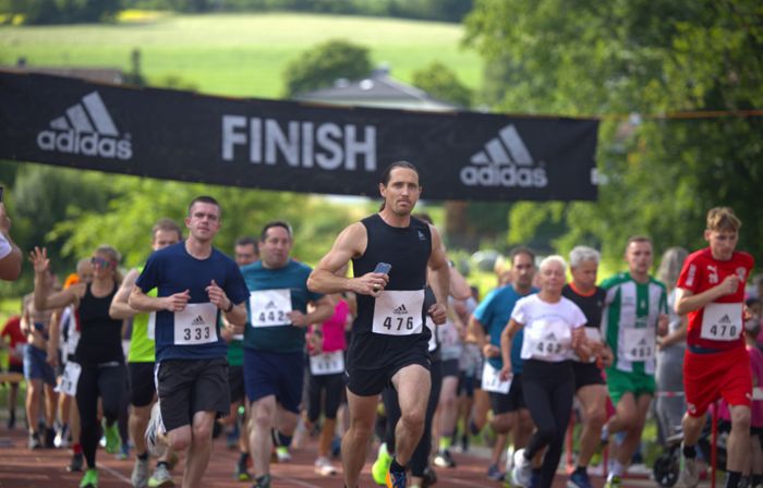 Läufer überqueren die Ziellinie beim Cross- und Querlauf in Oberbrügge. Arwed Weigel mit Startnummer 476 führt das Feld an.