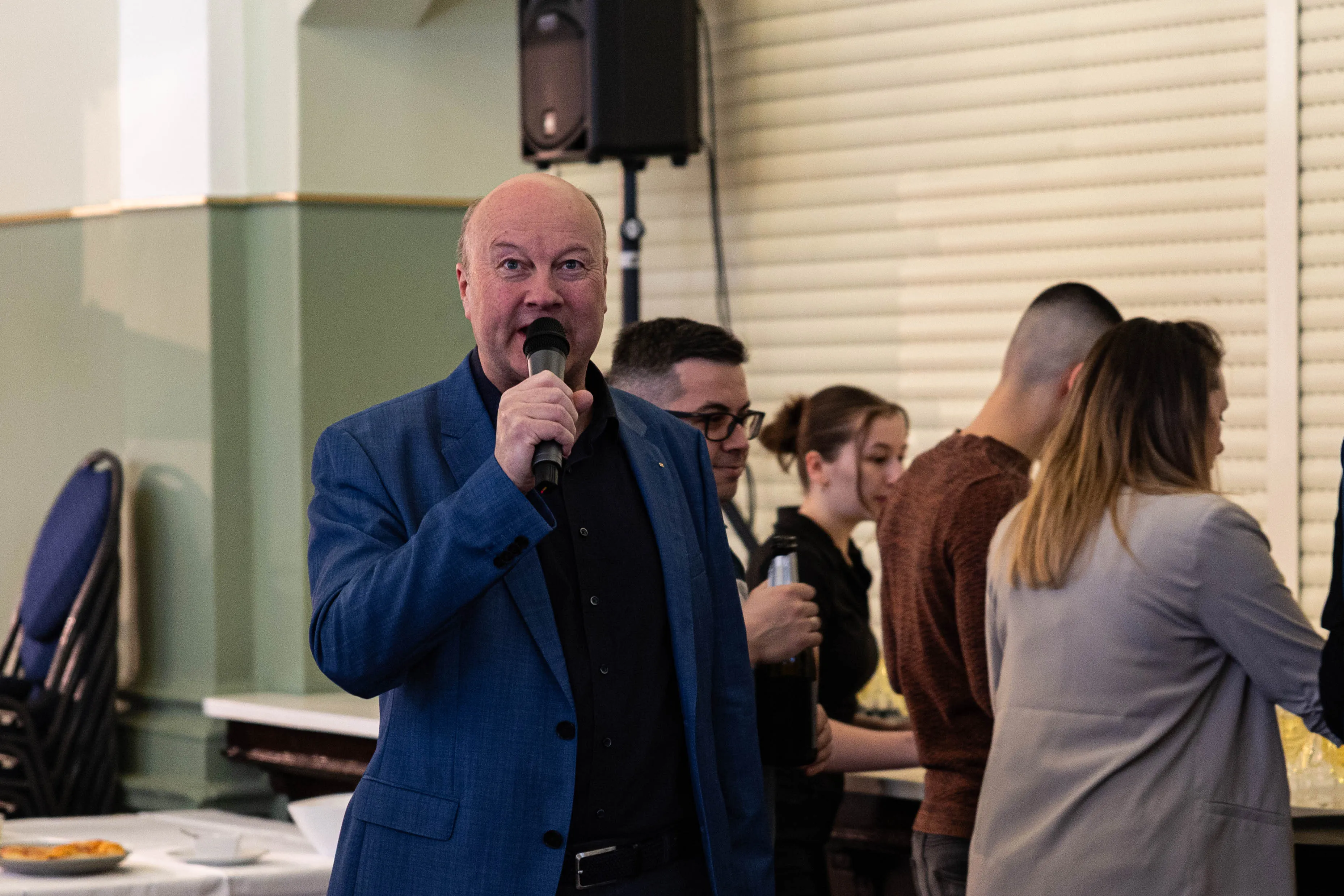 Martin Kornau, Vorsitzender der Bergstadt-Stiftung, spricht auf der Vernissage der „Art meets Antique“-Messe in Lüdenscheid in einen Mikrofons. Im Hintergrund stehen weitere Besucher.