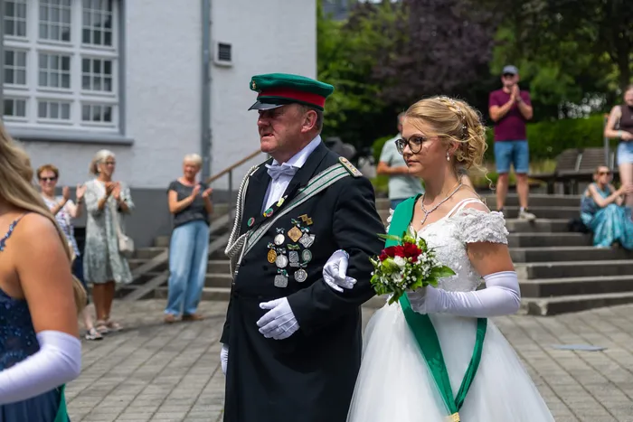 Stefan Schneider, der neue König der Meinerzhagener Schützengilde, geht in Uniform mit Orden und grüner Kappe arm in arm mit einer Frau in weißem Kleid.