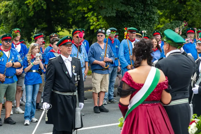 Stefan Schneider in schwarzer Galauniform mit Orden und Säbel steht vor Mitgliedern der Schützengilde in blauen Uniformen.