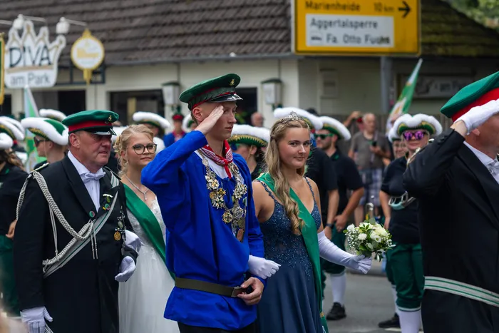 Stefan Schneider in blauer Uniform mit grüner Mütze und prunkvoller Kette salutiert bei der Feier der Meinerzhagener Schützengilde.