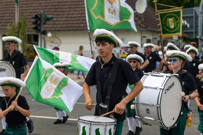 Mitglieder der Meinerzhagener Schützengilde in Uniform ziehen mit Trommeln und Fahnen durch die Straßen.