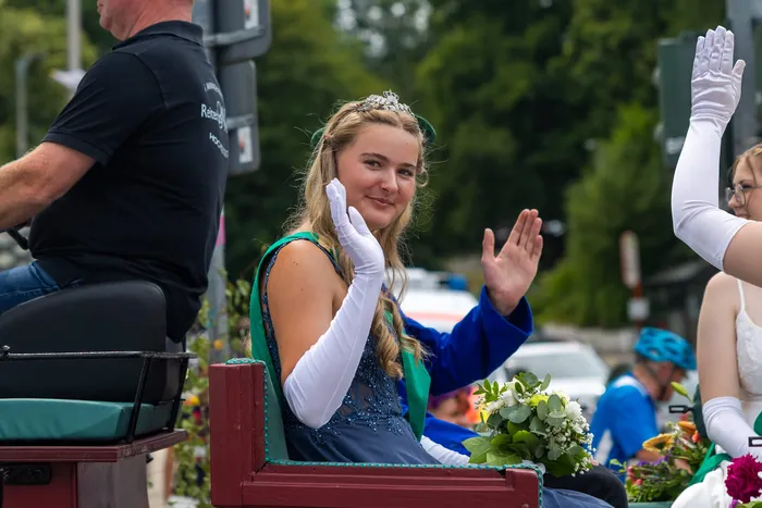 Eine junge Frau mit Tiara und langen weißen Handschuhen winkt in einem Festwagen während der Feier der Meinerzhagener Schützengilde.