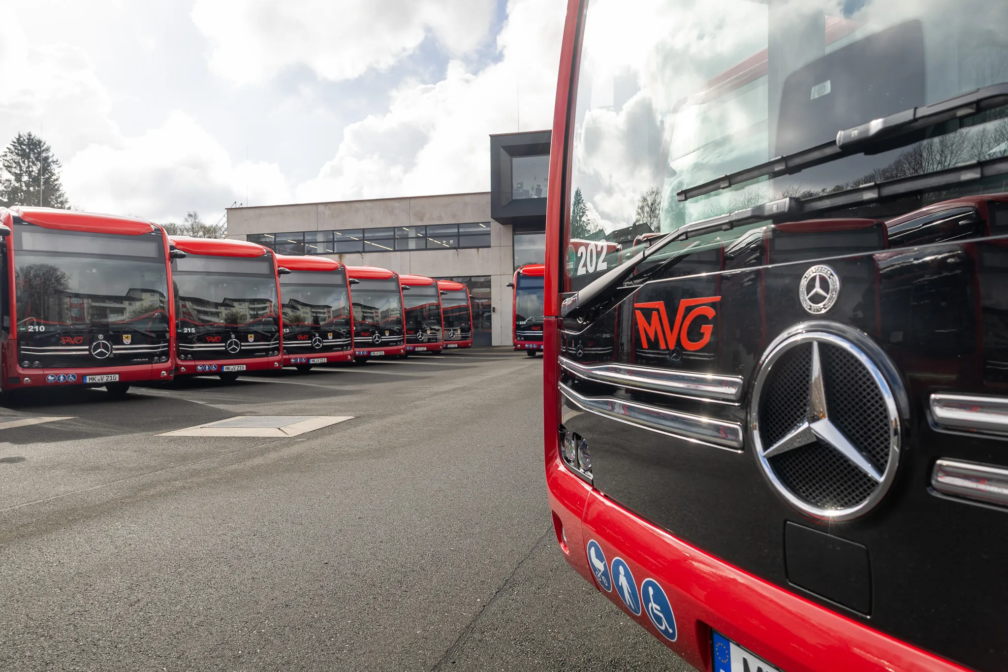 Reihe roter Elektrobusse der Münchner Verkehrsgesellschaft (MVG) auf einem Betriebshof, darunter ein Bus im Vordergrund mit dem Mercedes-Stern und der Nummer 202.