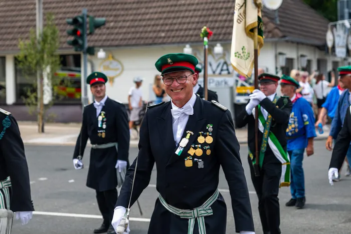 Stefan Schneider in dunkler Schützenuniform mit grüner Mütze und mehreren Orden lächelt.