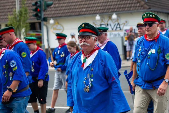 Stefan Schneider in blauer Uniform und grüner Mütze steht inmitten von Mitgliedern der Meinerzhagener Schützengilde.