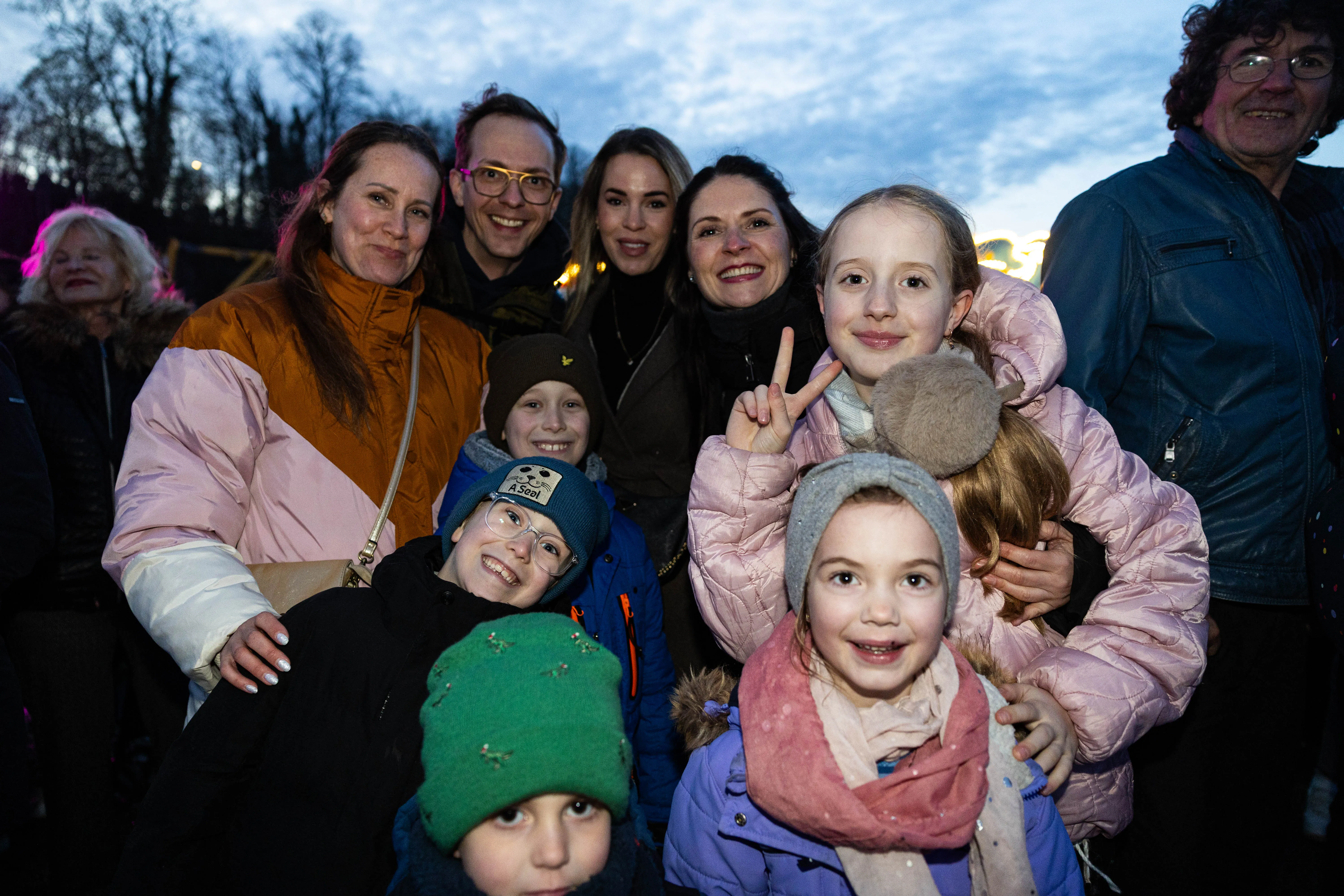 Eine Gruppe von Menschen unterschiedlichen Alters lächelt in die Kamera, im Hintergrund ein dunkler Himmel und Bäume. Das Bild zeigt eine Szene von der Osterfeuer-Veranstaltung „Burn the Fox“ in Lüdenscheid.