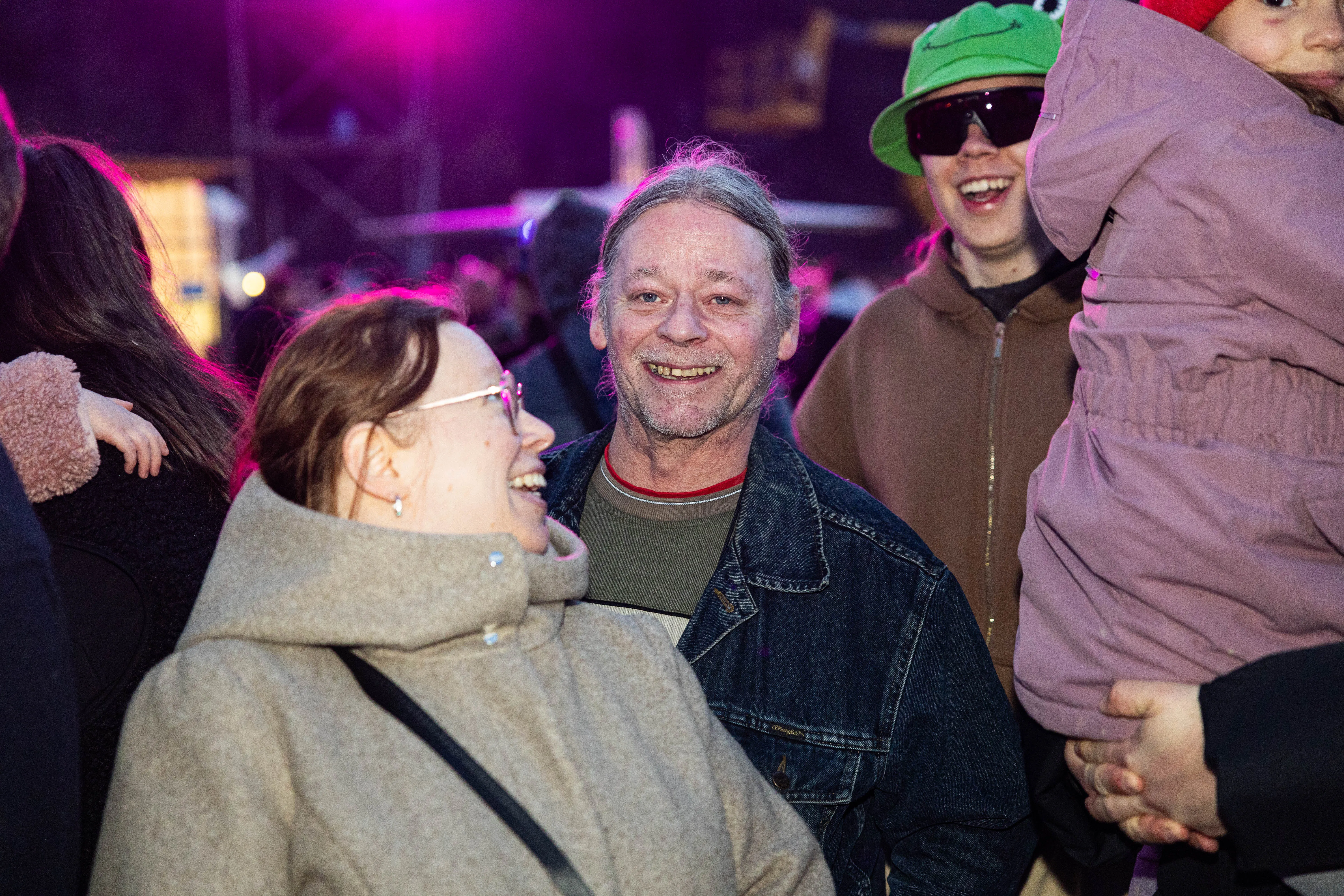 Lachender Mann mit grauen Haaren in Jeansjacke zwischen Besuchern auf dem Osterfeuer „Burn the Fox“ in Lüdenscheid.
