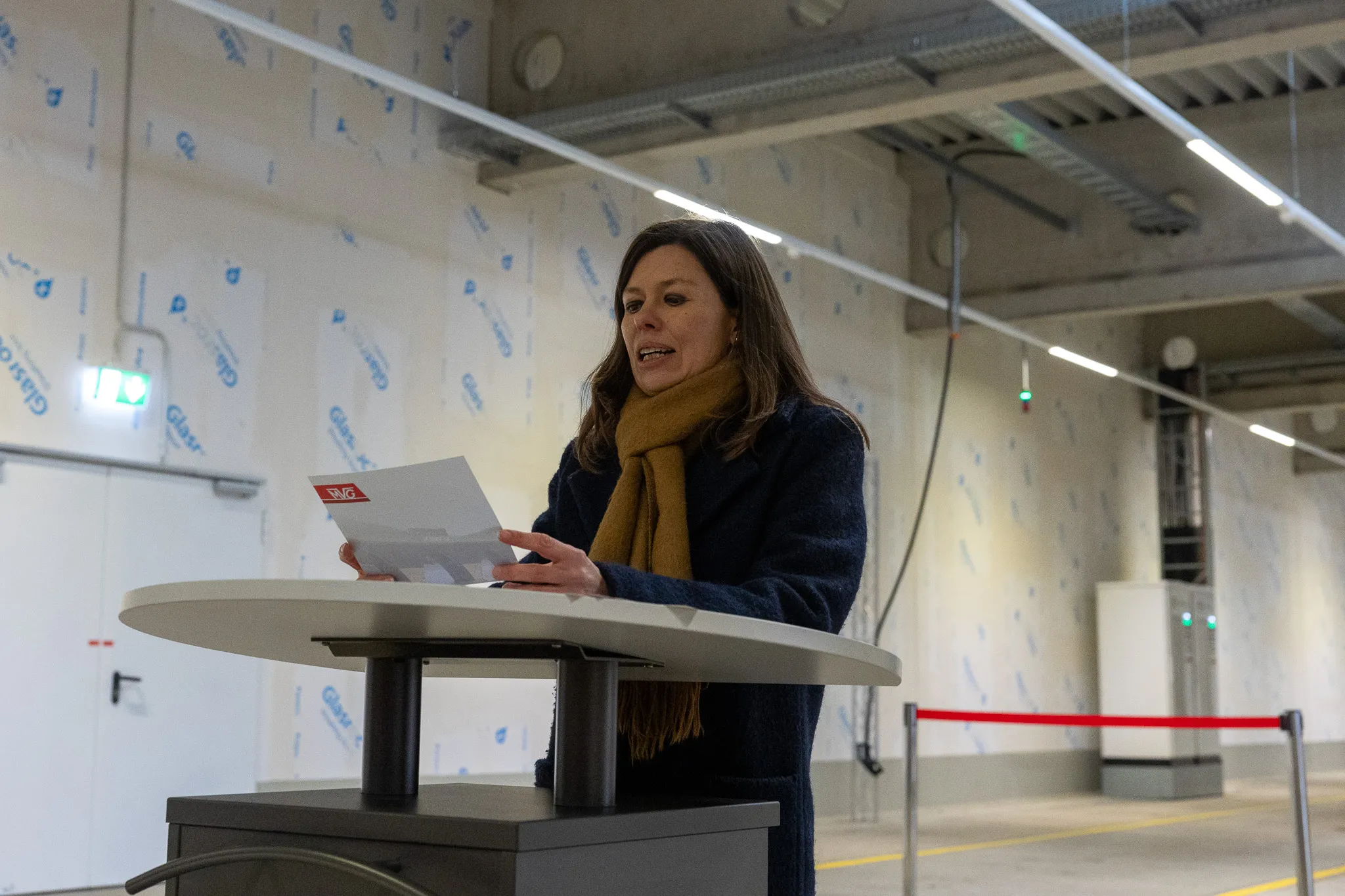 Frauke Effert, Geschäftsführerin der MVG, spricht mit Papieren in der Hand an einem Rednerpult in einem hellen Raum.