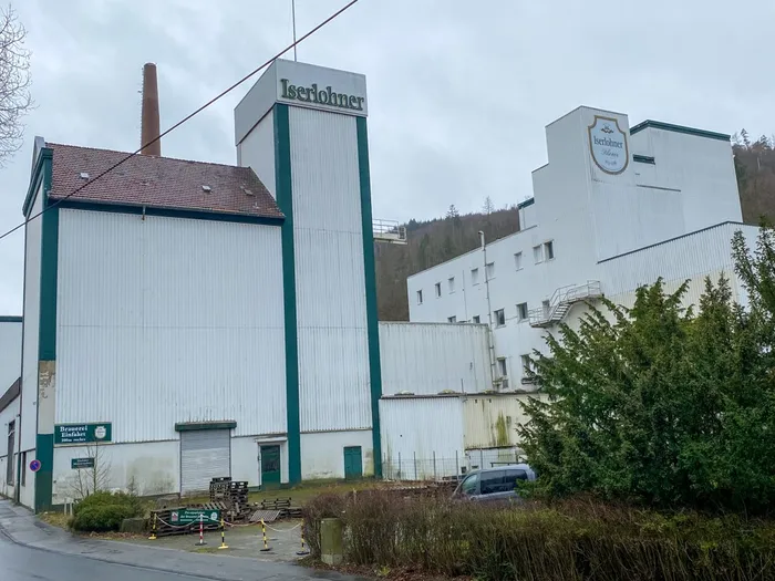 Das ehemalige Gebäude der Iserlohner Brauerei mit weißer Fassade, grünen Akzenten und dem Schriftzug „Iserlohner“ auf einem Turm.