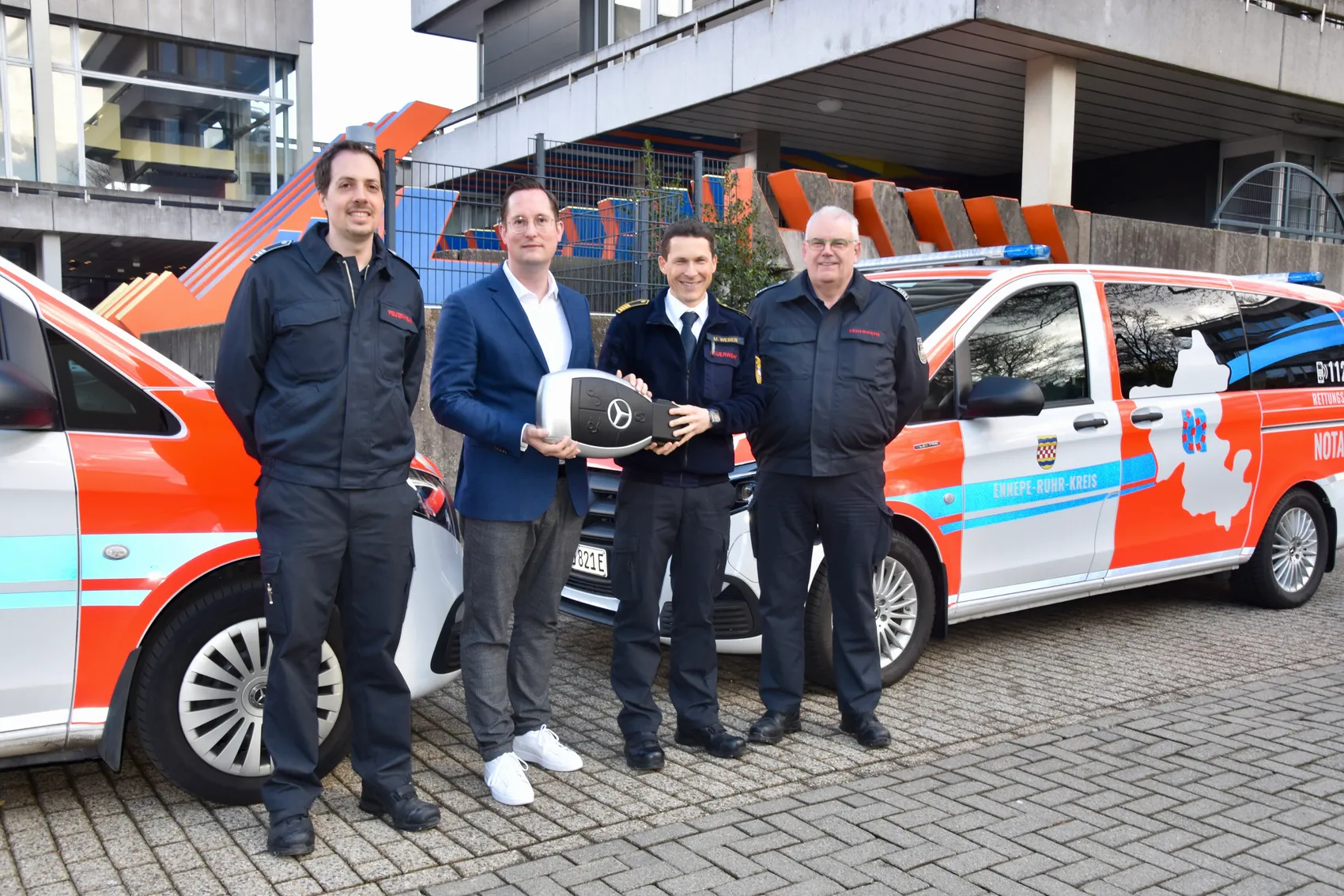 Landrat Jan-Christoph Schaberick übergibt symbolisch den Schlüssel für ein neues Notfallfahrzeug an Martin Weber, flankiert von Robin Nüllig und Thomas Knutzen.