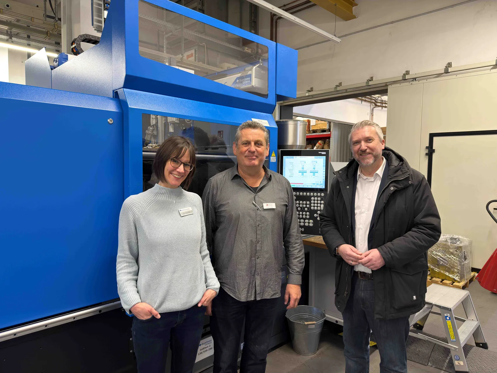 Drei Personen stehen vor einer großen blauen Maschine in einer Werkshalle. Von links: Karina Schiweck, Torsten Urban und Bürgermeister Sebastian Wagemeyer.