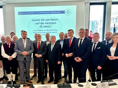 Eine Gruppe von etwa 15 Männern und einer Frau in formeller Kleidung posiert vor einem Banner mit der Aufschrift „Lassen Sie uns feiern – auf die nächsten 25 Jahre!“. Zu den Personen gehören Landrat a.D. Aloys Steppuhn, Landrat a.D. Thomas Gemke und Bundestagsabgeordneter Paul Ziemiak.