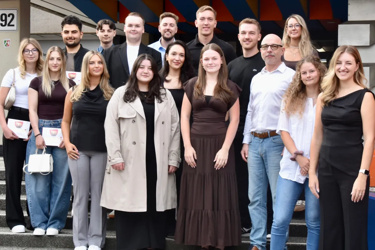 Eine Gruppe von etwa vierzehn Personen posiert gemeinsam auf einer Treppe vor einem Gebäude.