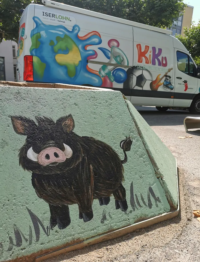 Malerei eines schwarzen Wildschweins auf einer hellgrünen Betonstruktur.
