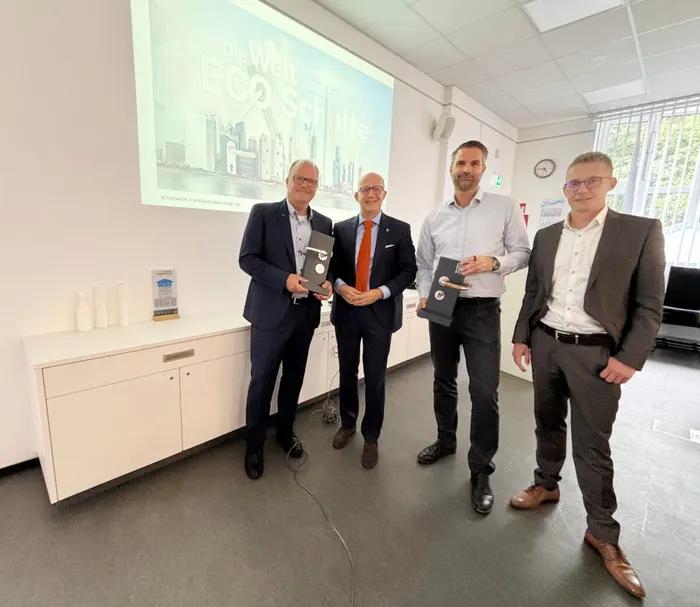 Heinz Schulte, Landrat Ralf Schwarzkopf, Tobias Schulte und Marcel Krings halten Auszeichnungen vor einer Projektion mit dem Schriftzug „Die Welt von ECO Schulte“.