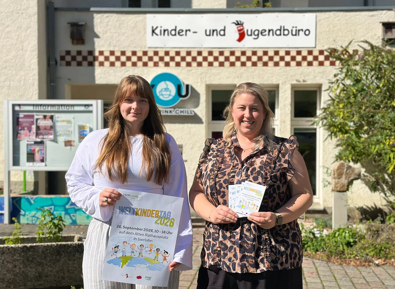 Vanessa Weicht und Kirstine Adebahr halten ein Plakat und Flyer für den Weltkindertag 2026 vor dem Kinder- und Jugendbüro.