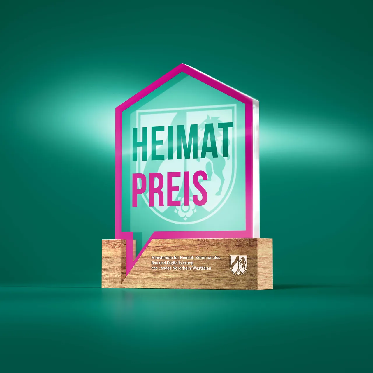 Hausförmige Trophäe mit der Aufschrift „HEIMAT PREIS“ auf einem Holzsockel des Ministeriums für Heimat, Kommunales, Bau und Digitalisierung Nordrhein-Westfalens.
