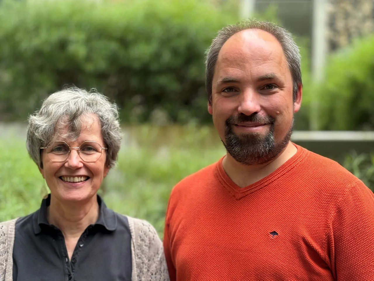 Die Regionalforscher Barbara Schneider und Fabian Fechner lächeln in einem Porträt vor grünem Hintergrund.