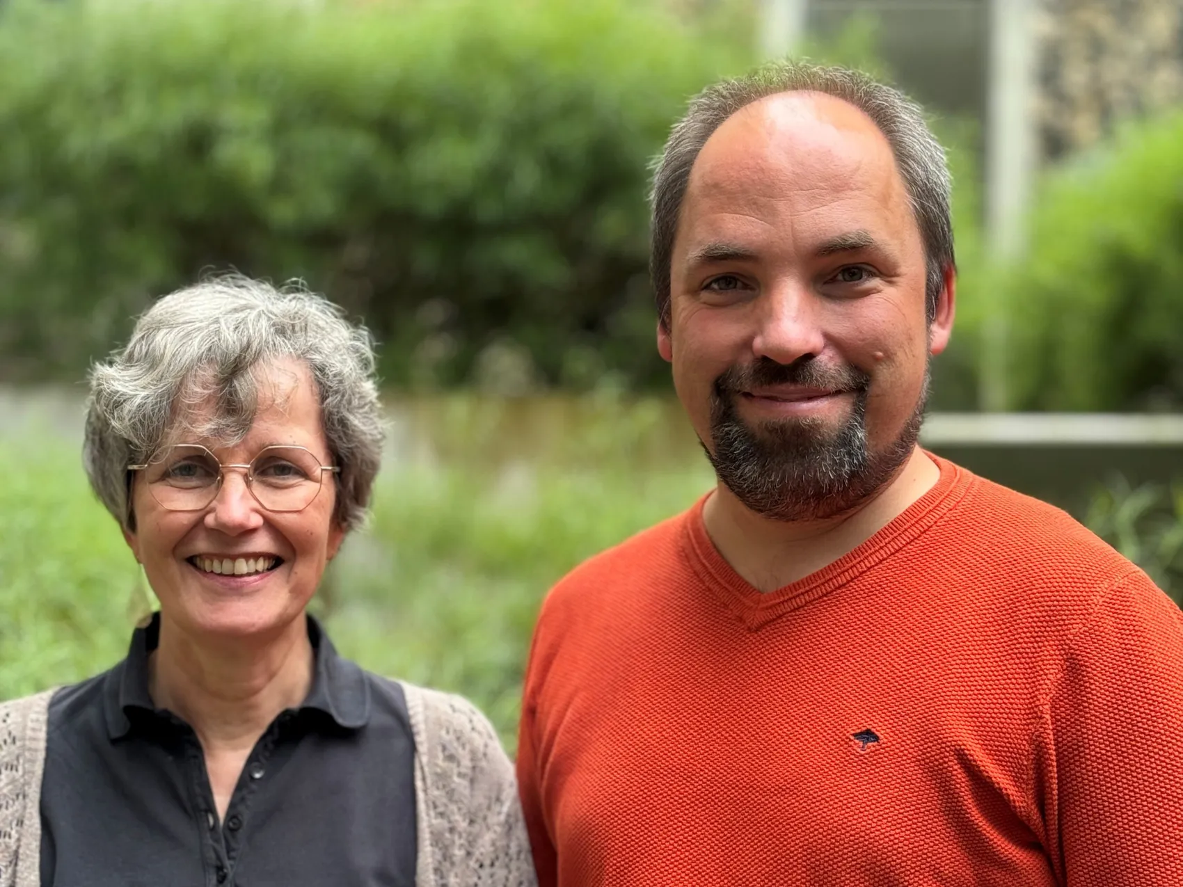 Die Regionalforscher Barbara Schneider und Fabian Fechner lächeln in einem Porträt vor grünem Hintergrund.