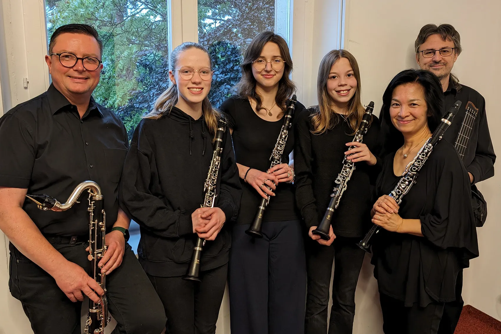 Sechs Mitglieder des Klarinettenensembles „The Blackstix“ posieren in schwarzer Kleidung mit ihren Klarinetten.