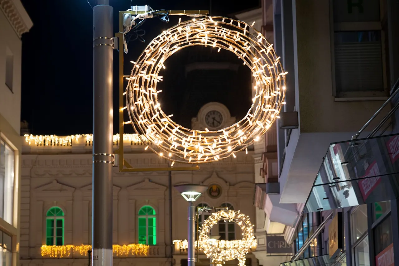 Ein großer, leuchtender Weihnachtskranz hängt nachts an einem Mast in der Iserlohner Innenstadt.