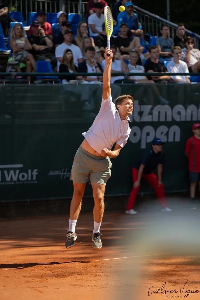 Ein Tennisspieler springt hoch, um einen Aufschlag auf einem Sandplatz bei den Platzmann Open auszuführen.