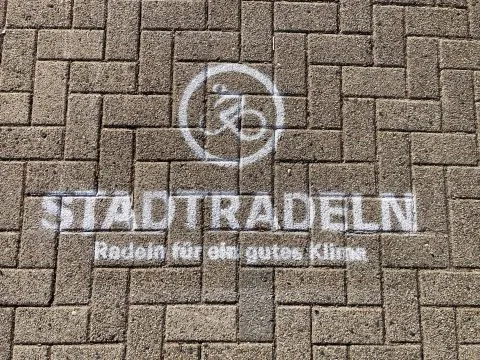 Kreidezeichnung auf Pflastersteinen mit dem Stadtradeln-Logo und dem Slogan „Radeln für ein gutes Klima“.