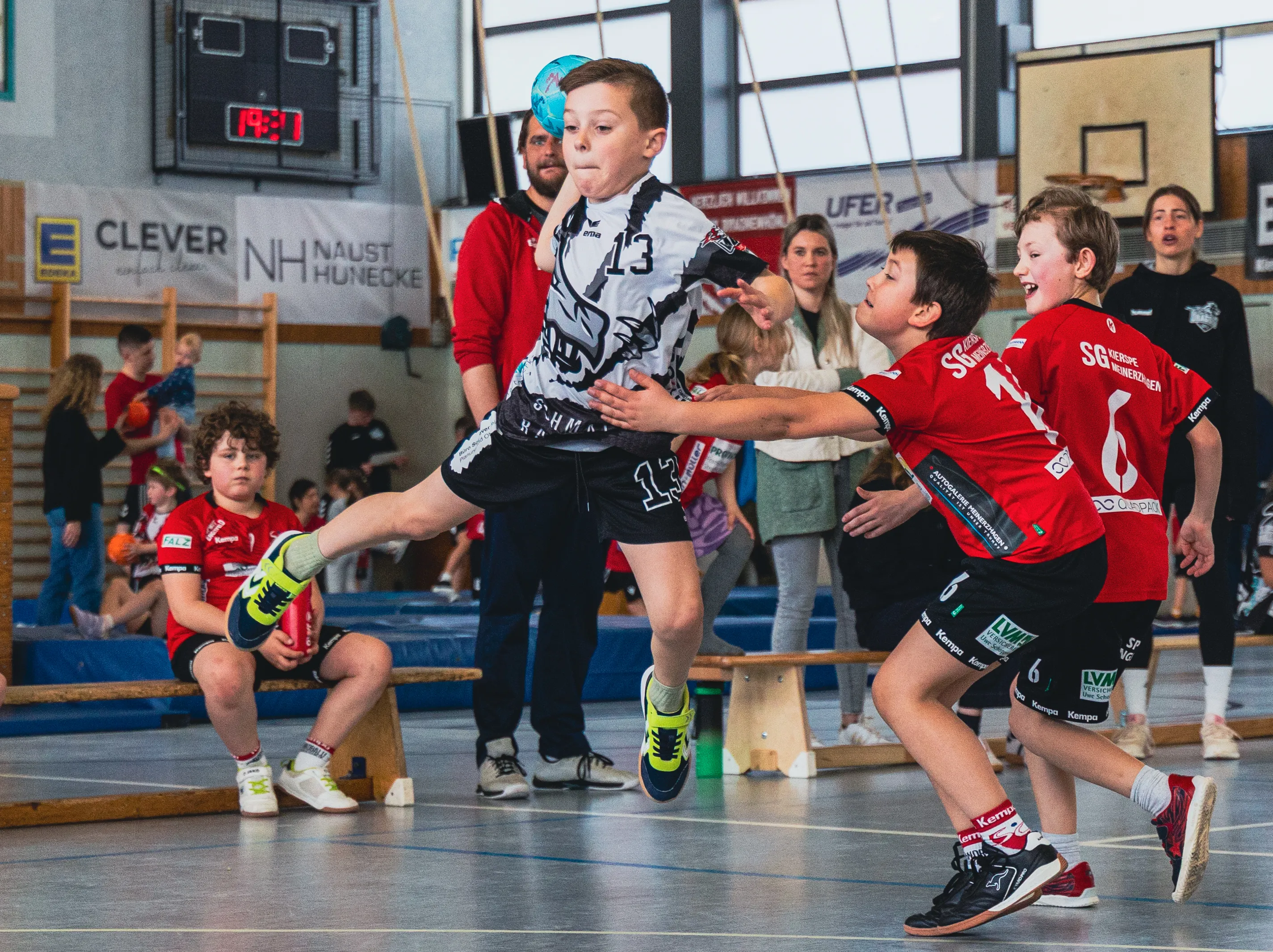 Handballspieler in Aktion während eines Spiels der F-Jugend der SGSH Dragons. Ein Spieler springt zum Wurf, während ein Gegenspieler ihn verteidigt.