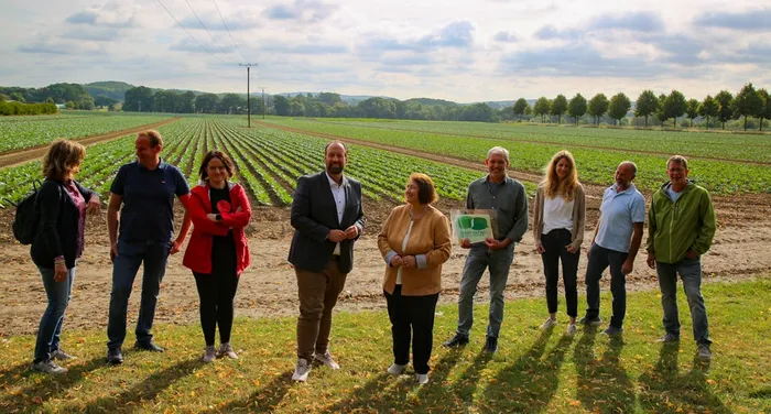 Neun Personen stehen in einer Reihe vor weitläufigen Gemüsefeldern auf dem Hof Drepper.