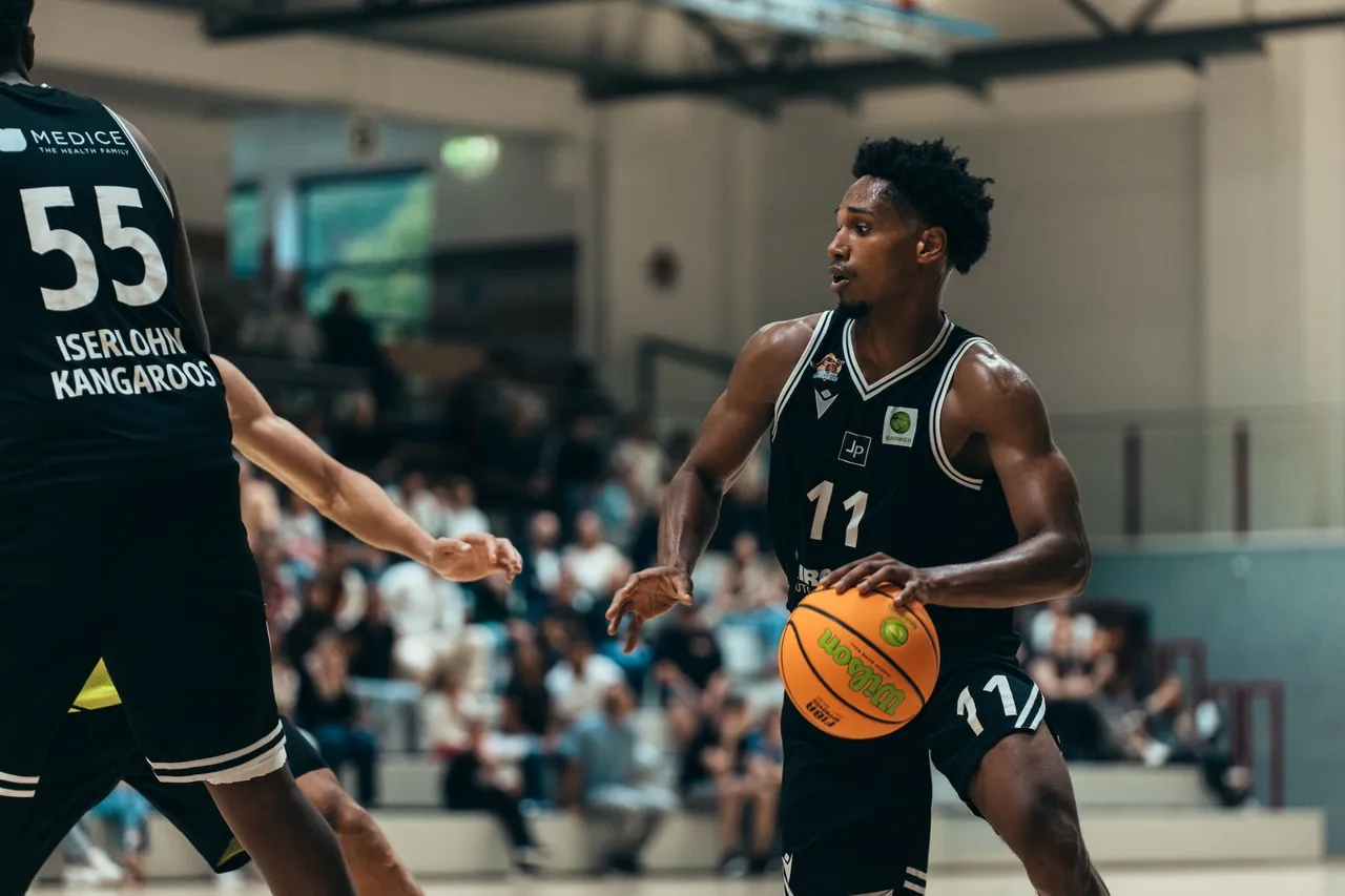 Ein Basketballspieler der Iserlohn Kangaroos mit der Nummer 11 dribbelt den Ball während eines Spiels in einer Sporthalle.