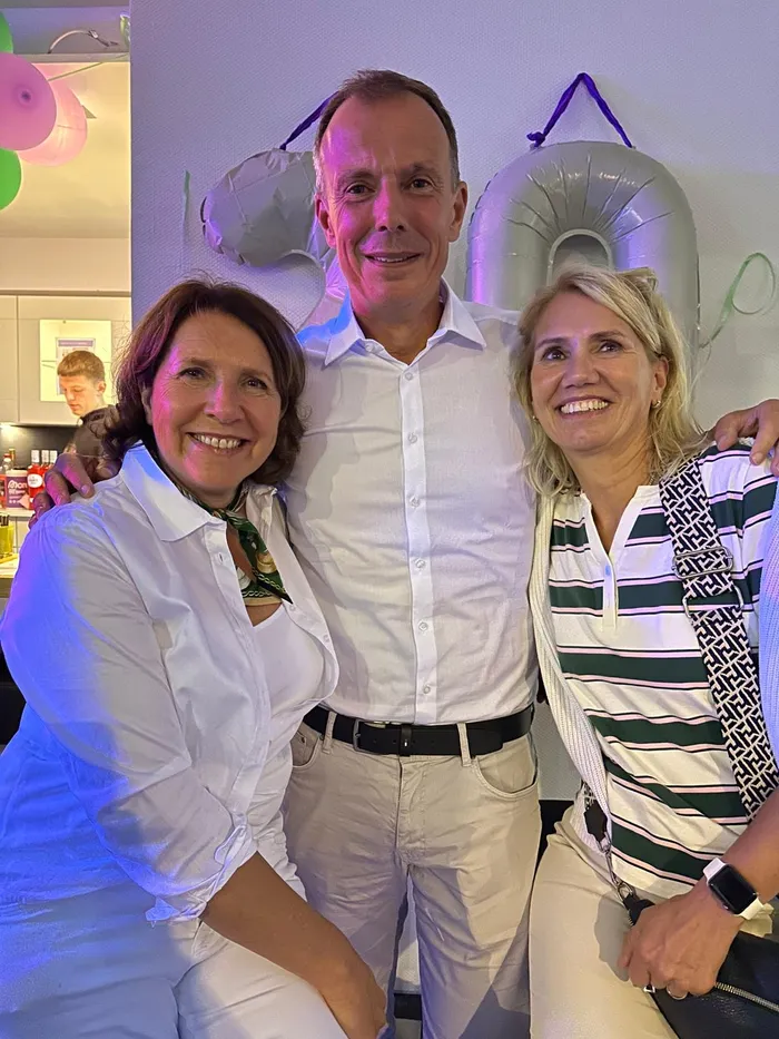 Ein Mann und zwei Frauen lächeln gemeinsam bei der „Party à la Wimbledon“ im Tennisclub Halver.