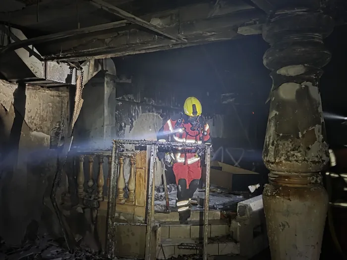 Ein Feuerwehrmann in Schutzkleidung steht in der dunklen, durch Brand beschädigten Schnörrenbach-Ruine vor einer Holzbalustrade.