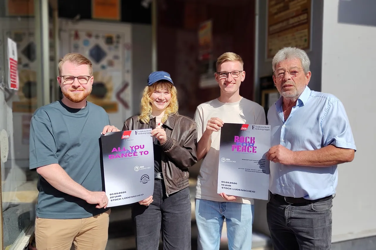 Vier Personen halten Plakate für die Veranstaltung „Rock for Peace“ hoch.