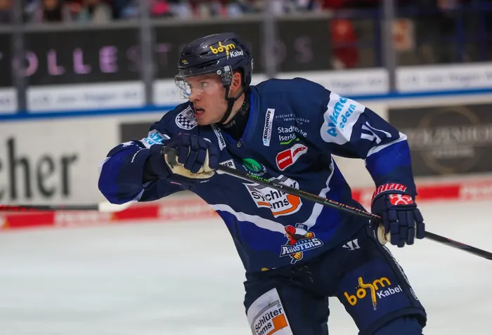 Maximilian Eisenmenger in blauem Eishockey-Trikot mit Helm und Visier auf dem Eis.