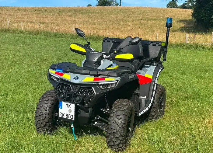 Ein Quad des DRK mit Blaulicht und gelb-roten Warnmarkierungen steht auf einer grünen Wiese.