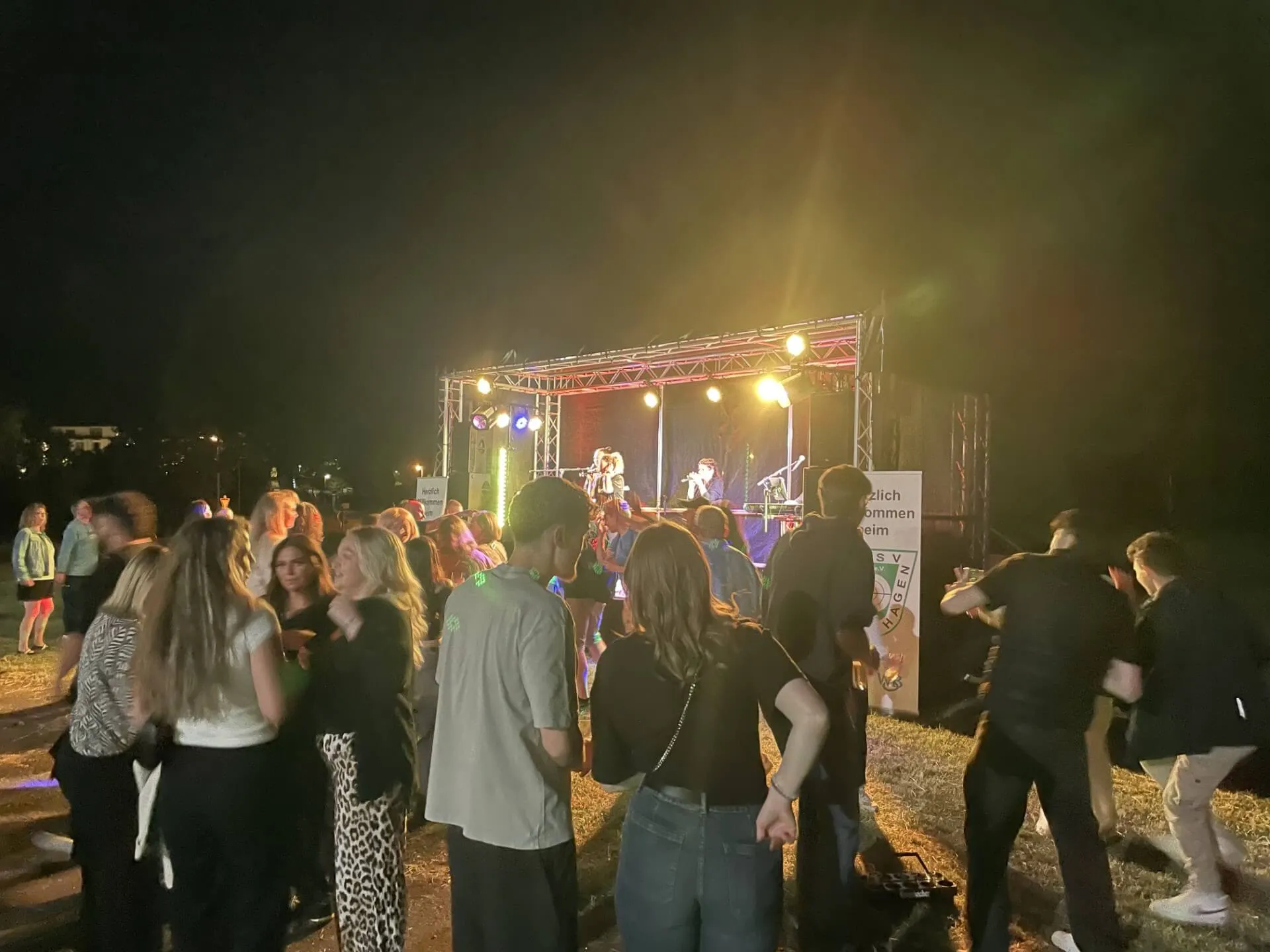 Bühne mit Band bei Nacht, davor eine große Menschenmenge, die das Konzert verfolgt. Im Hintergrund ein Werbebanner des KKSV Meinerzhagen.