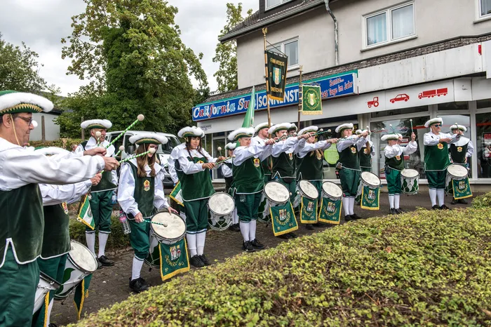 Mitglieder des Schützenvereins ASV Kierspe in grünen Uniformen spielen Trommeln bei einem Festumzug.