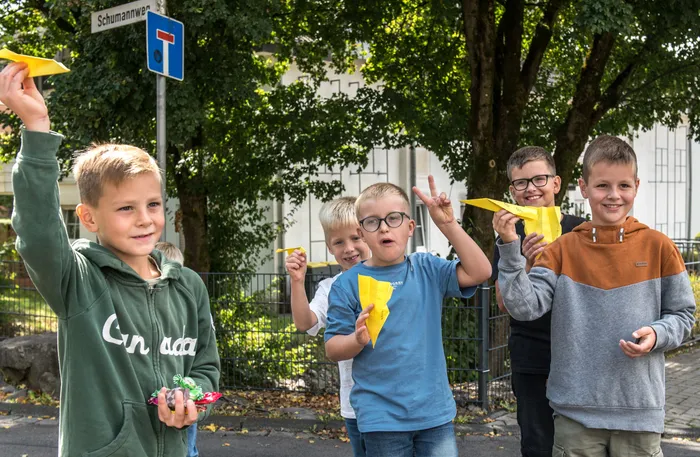 Mehrere Jungen halten gelbe Papierflieger in die Höhe während des Festumzugs des Schützenvereins Kierspe.