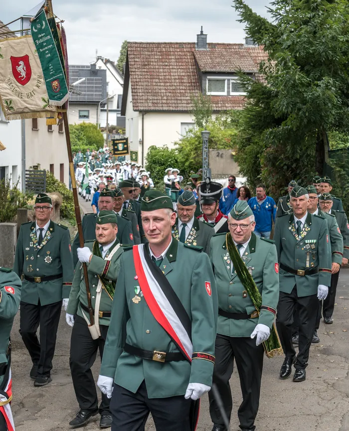 Mitglieder des Schützenvereins ASV Kierspe in grünen Uniformen mit Schärpen und Orden ziehen bei einem Festumzug durch eine Straße.