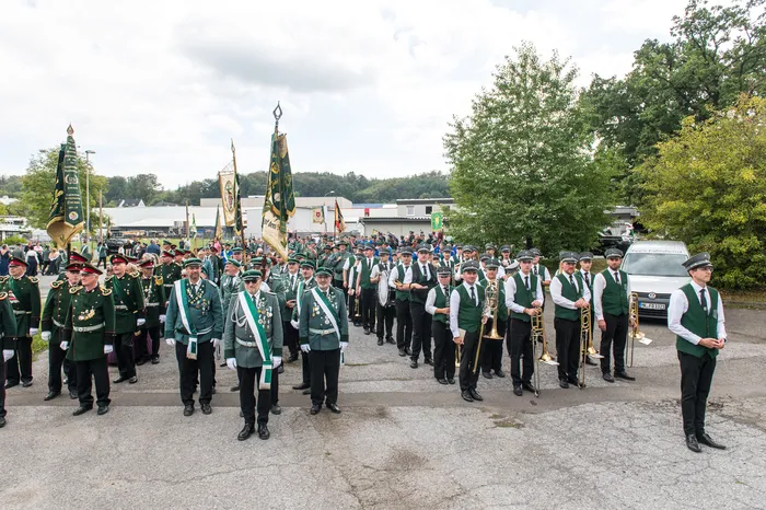 Mitglieder des Schützenvereins ASV Kierspe in grünen Uniformen stehen mit Blasinstrumenten und Fahnen bei einem Festumzug.