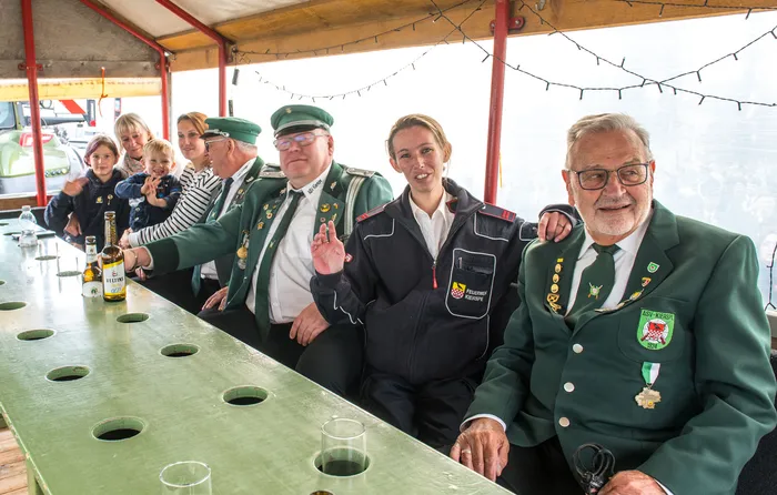 Mitglieder des Schützenvereins ASV Kierspe in grünen Uniformen und eine Feuerwehrfrau sitzen an einem langen grünen Tisch.