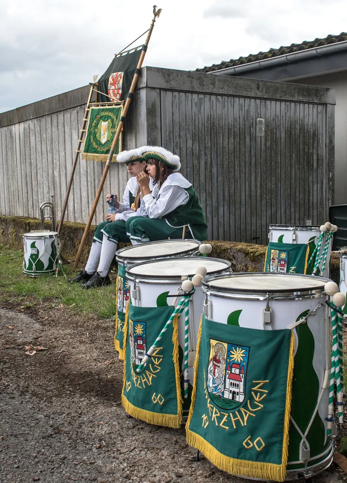 Zwei Personen in grün-weißen Uniformen und Pelzmützen sitzen hinter großen, verzierten Trommeln beim Schützenfest in Kierspe.